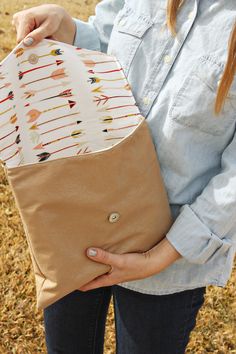 a woman holding an envelope with arrows on it in front of some grass and trees