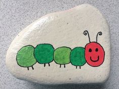 a painted rock with the very hungry caterpillar on it's side and smiling face