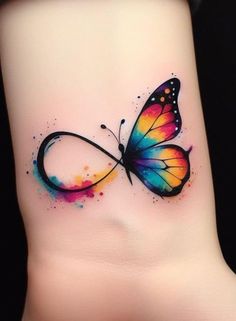 a colorful butterfly tattoo on the side of a woman's wrist with watercolor paint