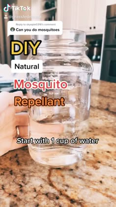 a person holding a jar with water in it on top of a kitchen countertop