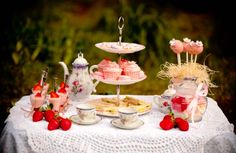 a table topped with cakes and cupcakes on top of a white table cloth