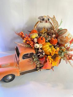 an orange truck filled with lots of fall flowers and birds sitting on top of it