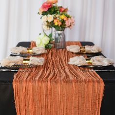 the table is set with plates and napkins on it, along with flowers in a vase