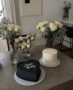 two cakes sitting on top of a table next to vases filled with white flowers