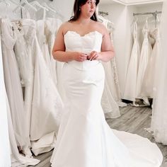 a woman in a wedding dress looking at herself in front of the bridal gowns