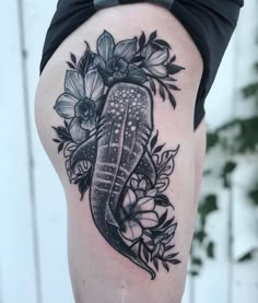 a woman's thigh with flowers and an ornate tattoo design on her leg,