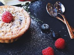 raspberry and blueberry muffins on a black surface with spoons