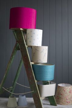 several rolls of toilet paper are stacked up on a wooden stand next to a pink lamp