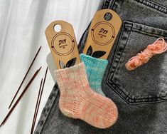 two pairs of socks with knitting needles next to them and yarn in the back pocket