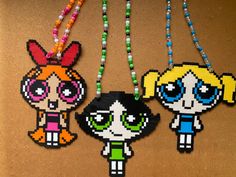 three beaded necklaces with cartoon characters hanging from it's sides on a brown surface