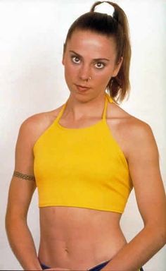 a woman in a yellow top is posing for a photo with her hands on her hips