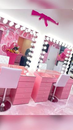 a pink vanity table with two white chairs in front of it and a mirror on the wall