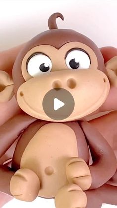 a hand holding a toy monkey with eyes wide open and tongue sticking out to the side