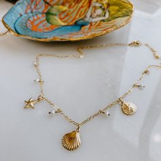 The Coast Trip Charm Necklace gives all the ocean vibes! Treasures from the sea- mini freshwater pearls plus charms of a starfish, clam shell and a sand dollar. Choose your length for the perfect fit! Available in 14k gold fill 16", 18" or 20" length available. Gold Shell Necklace With Starfish Charm For Vacation, Gold Starfish Shell Necklace With Starfish Charm, Gold Shell Necklace With Starfish Charm, Shell Starfish Charm Necklace, Gold Starfish Shell Necklace, Gold Shell With Starfish Charm For Beach, Gold Starfish Shell For Beach, Gold Starfish Jewelry With Pearl Charm, Sand Dollar Pendant