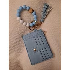 a small blue wallet with a tassel on it's keychain and a beaded charm