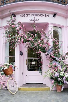 a pink bicycle parked in front of a building with flowers growing on it's side