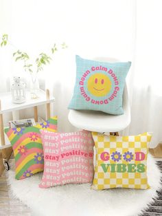 four colorful pillows sitting on top of a white chair next to a potted plant