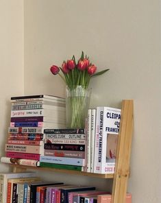 a book shelf filled with lots of books next to a vase full of tulips