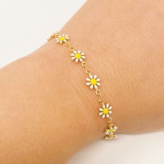 a close up of a person wearing a bracelet with daisies on the wrist and chain