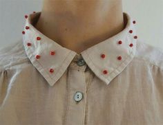 a close up of a person wearing a shirt with red beads on it's collar