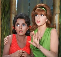 two women in green and red are posing for the camera