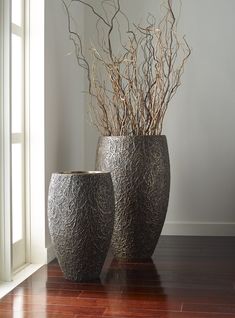 two large vases sitting on top of a hard wood floor next to a window