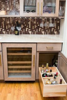 a kitchen with wine glasses and bottles in the cabinet drawer on the floor next to the counter