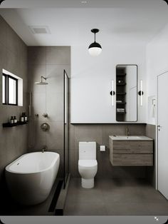 a white toilet sitting next to a bath tub under a bathroom mirror above a sink