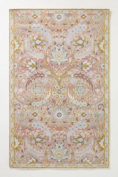 a pink and yellow rug with an ornate design on the bottom, in front of a white wall