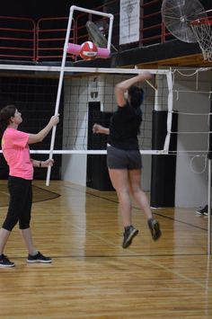 two women playing volleyball on an indoor court