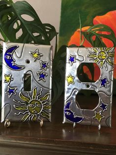 two metal letters with sun and moon designs on them sitting next to a potted plant