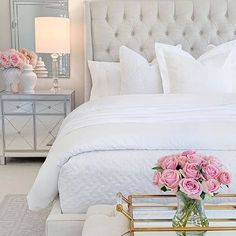 a white bed with pink roses in a vase