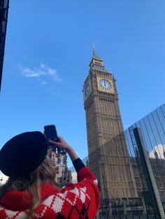 a woman taking a photo of the big ben clock tower