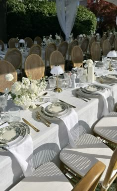 a table set with plates and silverware for an outdoor wedding reception in the sun