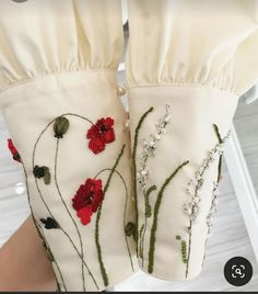 a pair of white gloves with red flowers on them