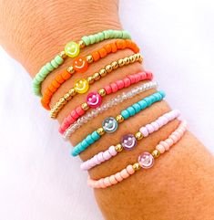 a woman's arm with different bracelets and smiley face charms on each wrist