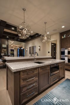 a large kitchen with an island and chandelier hanging from it's ceiling