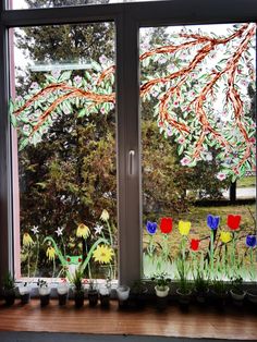 there are many flowers in the window sill by the grass and trees behind them