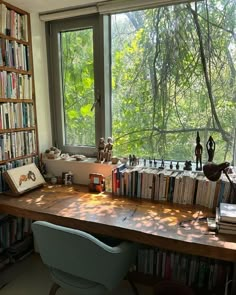 a desk with many books on it in front of a window filled with lots of books