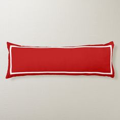 a red and white rectangular pillow on a wall