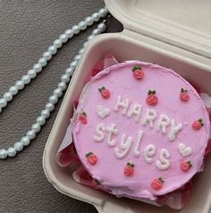 a pink cake in a plastic container with the words happy styles on it and strawberries