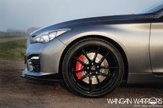 the front end of a silver car with red spokes and black rims on it