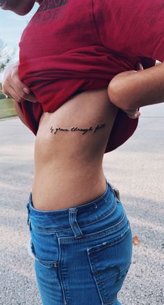 a woman's stomach with the word love tattooed on her lower back, in front of an empty parking lot