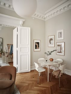 a white table and chairs in a room with pictures on the wall behind it,