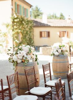 two wine barrels with flowers on them are set up for an outdoor ceremony in front of a house