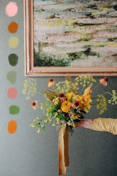 a woman holding a bouquet of flowers in front of a painting