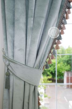 a curtain with tassels hanging from it's side in front of a window