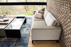 a living room filled with furniture and a brick wall next to a large glass window