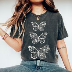 If you love all things flowers and butterflies, then our Vintage Garment Dyed Flower Shirt is perfect for you! Featuring a beautiful butterfly design and a soft, vintage feel, this Cottage Core T Shirt is a must-have for any gardener or nature lover. It's a great gift idea for your friends who are into the insect and fairycore trend. You'll adore the unique style and comfort of our Butterfly Top Fairycore Tee. DETAILS Comfort Colors introduces its garment-dyed t-shirt; a fully customizable tee made 100% with ring-spun cotton. The soft-washed, garment-dyed fabric brings extra coziness to your wardrobe while the relaxed fit makes it an excellent daily choice. The double-needle stitching throughout the tee makes it highly durable while the lack of side-seams helps the shirt retain its tubular Vintage Cotton Tops With Butterfly Print, Bohemian Cotton Tops With Butterfly Print, Spring Graphic Tee Hand Dyed, Hand Dyed Graphic Tee For Spring, Spring Hippie Hand-dyed T-shirt, Dye Flowers, Vintage Feeling, Butterfly T Shirt, Butterfly Top