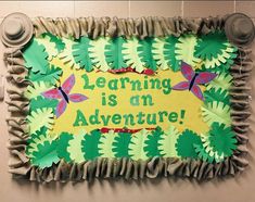 a bulletin board that says learning is an adventure surrounded by green leaves and butterfly shapes